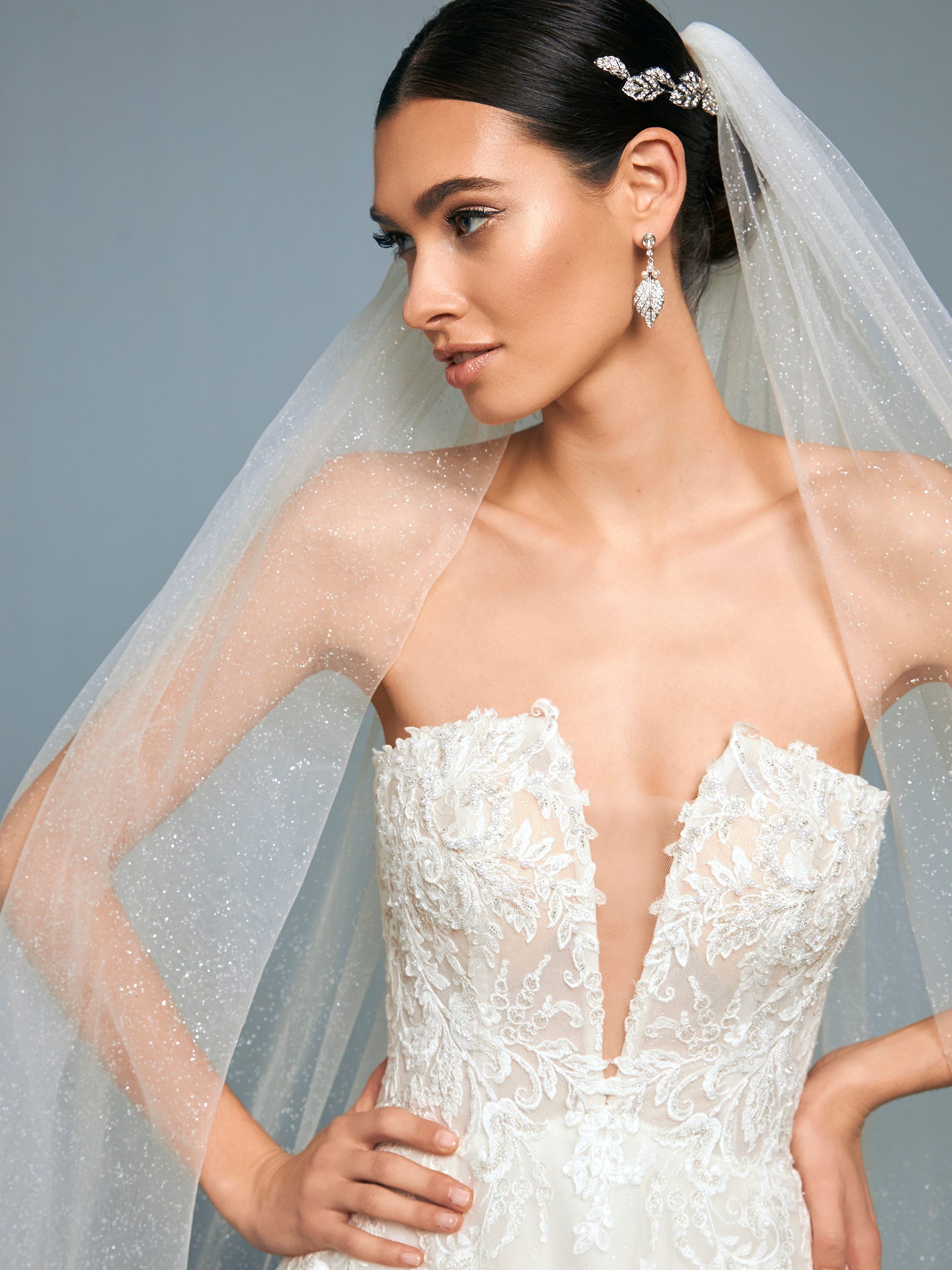 Mujer mirando de perfil con un vestido de novia, un mo&ntilde;o y un velo de novia catedral o capilla.
