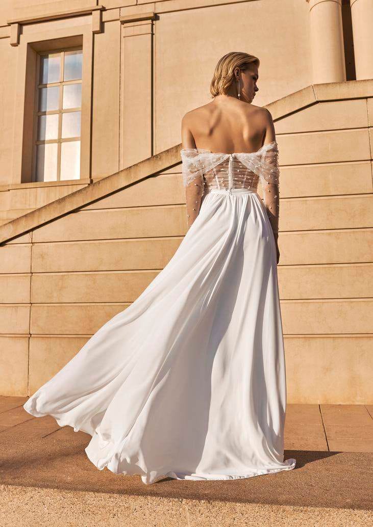 Blonde Frau von hinten mit schulterfreiem Brautkleid mit durchsichtigem Oberteil und Perlenapplikationen