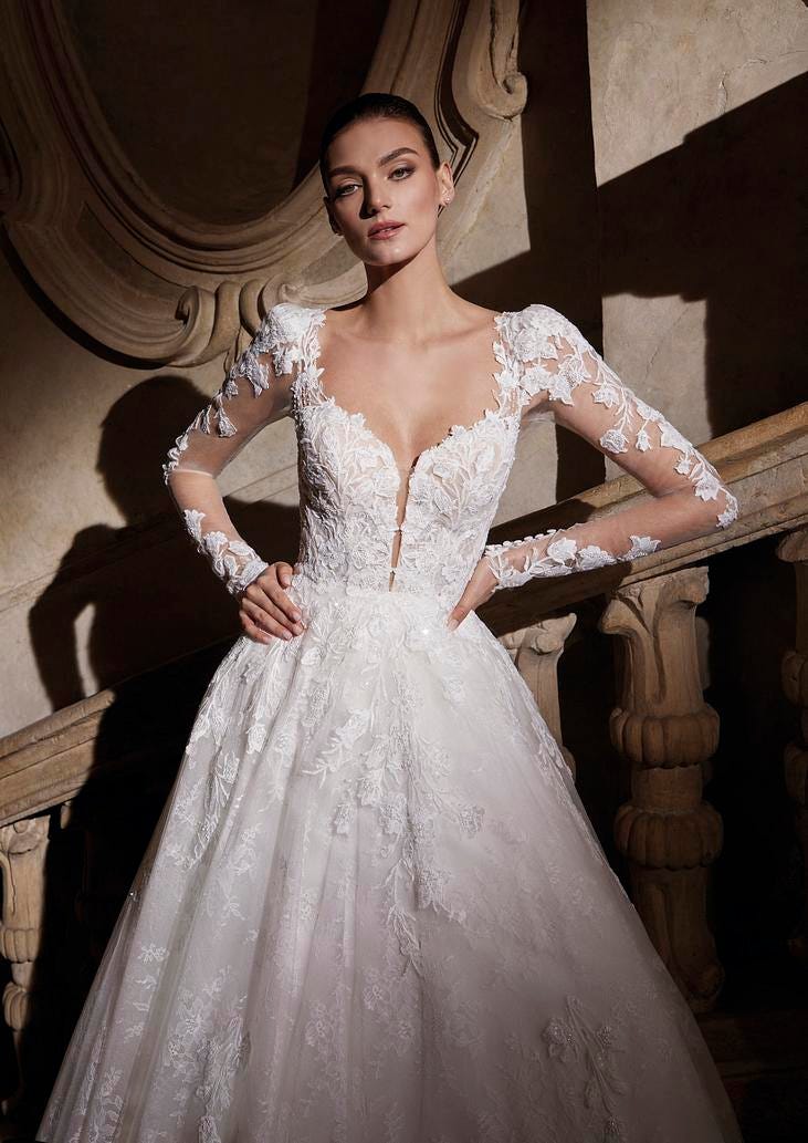 Woman wearing a tulle A-line wedding dress with a flowing lace skirt, standing on a staircase