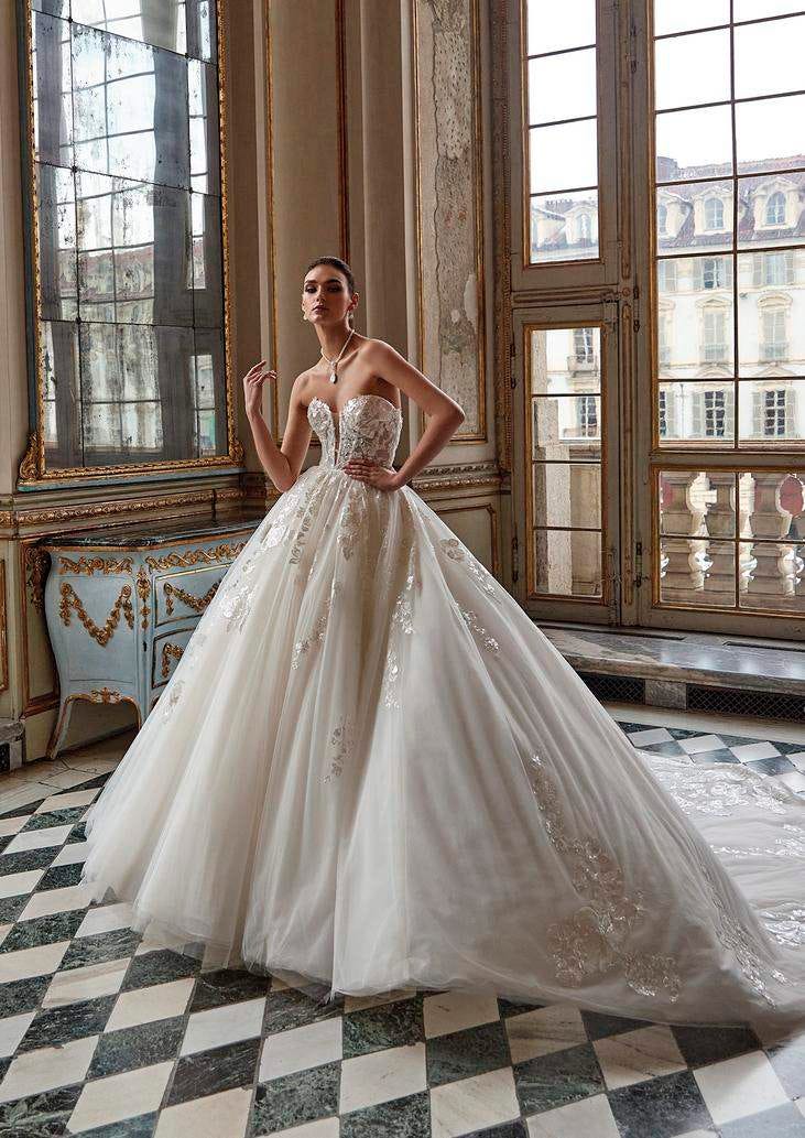 Woman wearing a romantic princess wedding gown with a volumunous layered skirt, standing in a ballroom