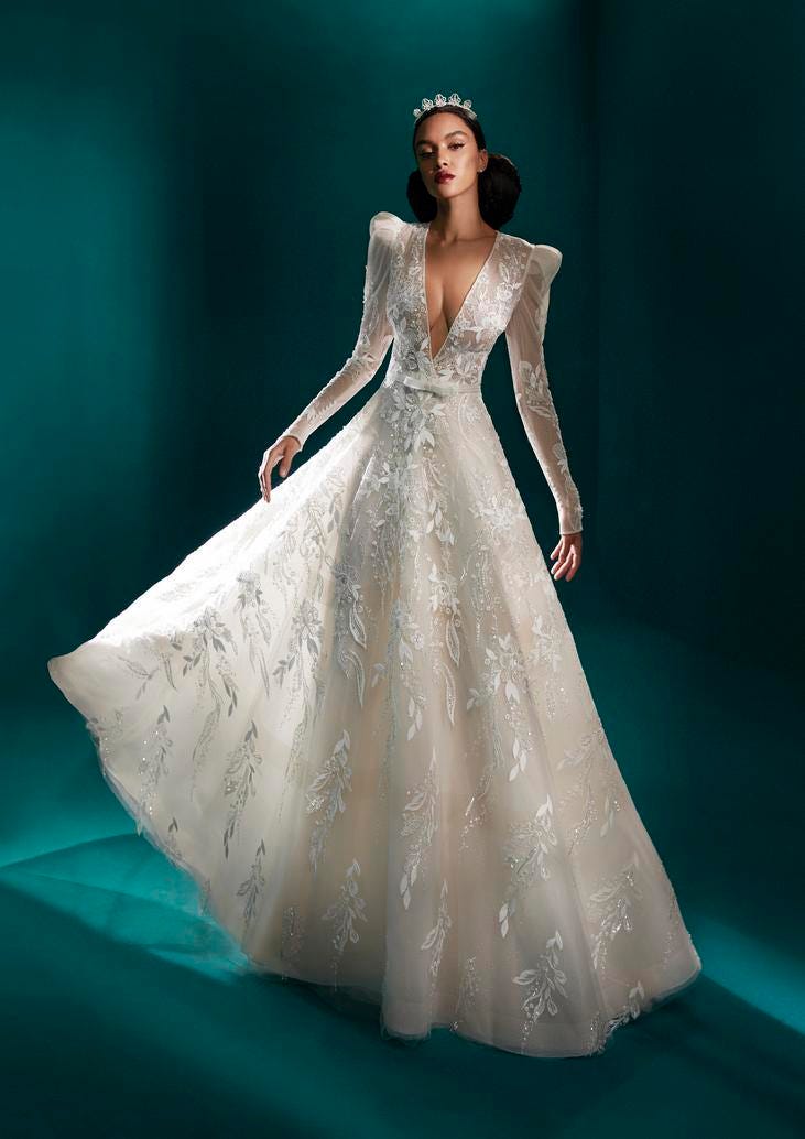 Woman wearing an embroidered A-line wedding dress with long sleeves and puff at the shoulders