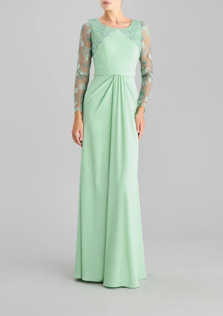 Woman wearing a sheath cocktail dress with long sleeves and crew neckline in georgette, standing against a grey background