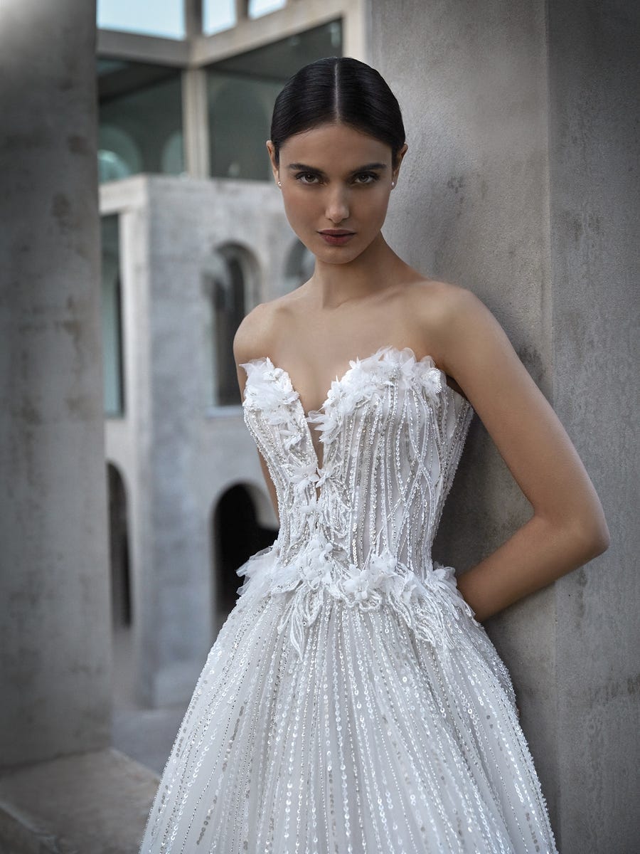 Vestido de novia con escote corazón Mujer luciendo un vestido de novia con escote de pico con el pelo recogido y mirando de frente.